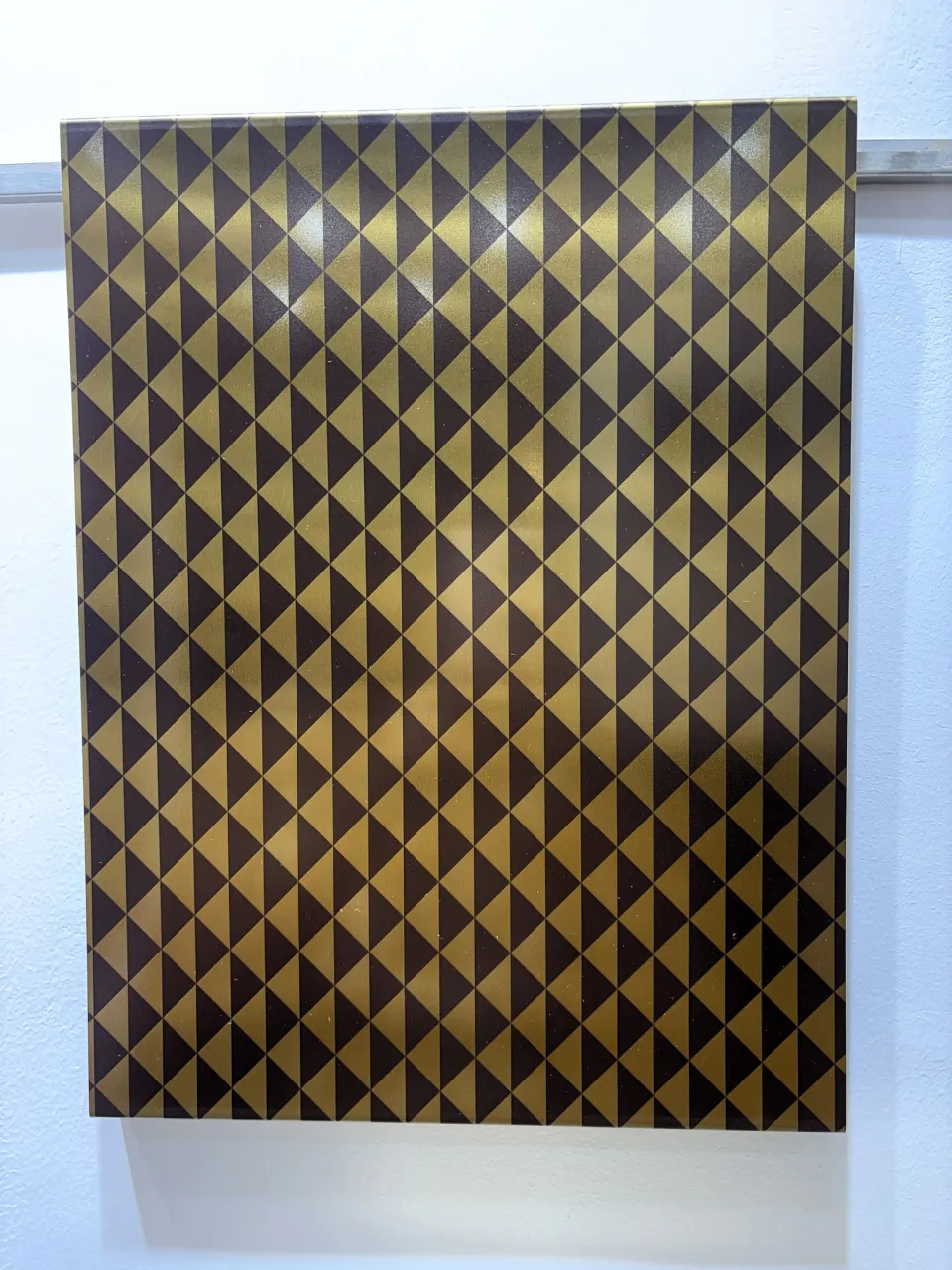 Etched triangle pattern on a gold stainless steel sheet